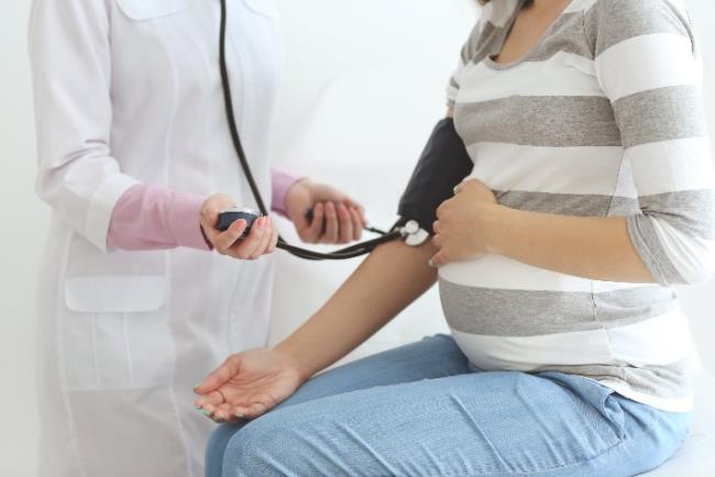 אישה בהריון סובלת מיתר לחץ דם גבוה בבדיקת לחץ דם אצל הרופאה המטפלת 